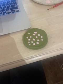 My first polymer clay creation. A coaster painted olive green with pink flowers painted on it.